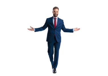 Mavi takım elbiseli genç adam beyaz arkaplan arkaplan arkaplanı ararken kollarını açıp birini selamlıyor.