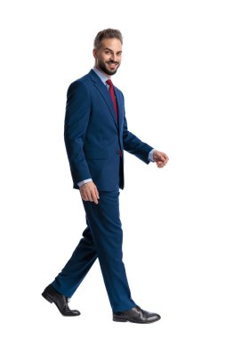 Side view of confident businessman walking and stepping while looking forward with a happy smile isolated on white background