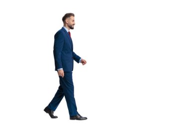 Lacivert takım elbiseli mutlu bir adam beyaz arka planda izole edilmiş bir gülümsemeyle yürüyor ve öne çıkıyor.