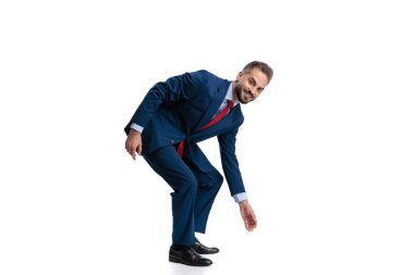 Mavi takım elbiseli arkadaş canlısı genç adam, beyaz arka planda izole edilmiş mutlu bir gülümsemeyle ileri doğru eğilip uzanıyor.