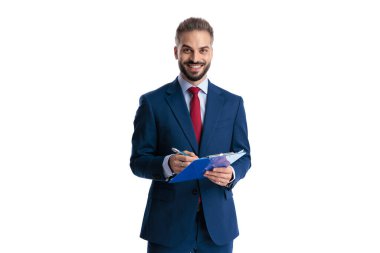 Mutlu iş adamı mavi panoya notlar yazıp gülümserken beyaz arka planda tek başına ileriye bakıyor.