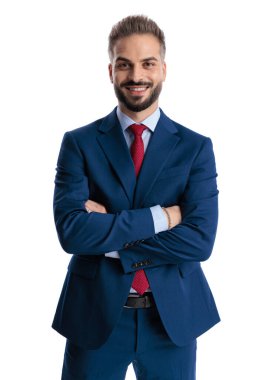 Confident businessman in blue suit standing with arms crossed and smiling while looking forward isolated on white background