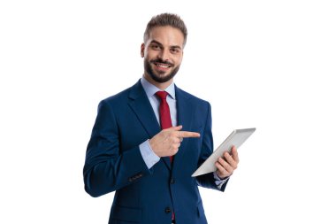 Neşeli iş adamı dijital tableti işaret ediyor ve beyaz arka planda ileriye bakıyor