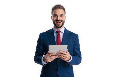 Heyecanlı iş adamı elinde dijital tabletle beyaz arka plana bakarken geniş bir gülümseme ile bakıyor.