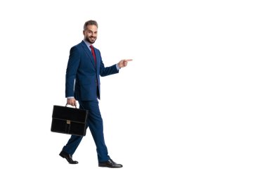Evrak çantası tutan mutlu iş adamının yan görünüşü. Parmakla göstermek ve beyaz arka planda izole bir şekilde ileriye bakmak.
