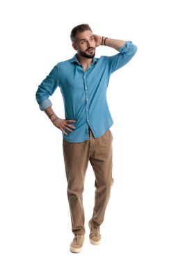 Kafası karışmış sakallı sıradan bir adam, burun halkası takan, başını kaşıyan, elini belinden tutan, başka tarafa bakan ve beyaz arka planda soyutlanmış biri olduğunu düşünen.