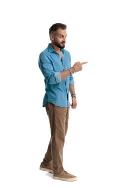 Kotlu gömlekli sıradan bir adamın beyaz arka planda izole edilmiş bir şekilde yürürken ve parmaklarını sağa sola gösterirken yan görünümü