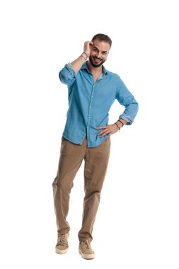 Kafasını kaşıyan mutlu bir adam, el ele tutuşup gülümserken beyaz arka planda ileriye bakıyor.