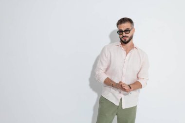 Tarz sahibi bir adam ileriye bakarken ve beyaz arka plan üzerinde çalışmaya hazırlanırken ellerini ovuşturuyor.