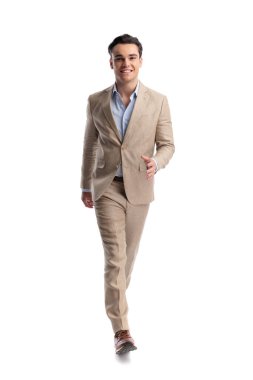 Beyaz bir arkaplanda ileriye bakarken bej renkli keten takım elbiseli, gülümseyen zarif bir adam.