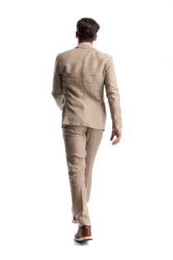 Bej renkli keten takım elbiseli şık bir adamın beyaz arka planda tek başına yürüyüp gidişinin arka planı.