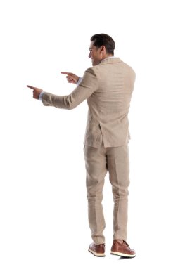 Arka tarafta bej renkli keten takım elbiseli mutlu bir adam var. İki elini de yana uzatıp beyaz arka planda izole bir şekilde geriye bakıyor.