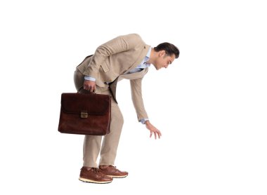 Beyaz arka planda izole edilmiş kahverengi deri evrak çantası tutan bej renkli keten takım elbiseli mutlu bir adam.