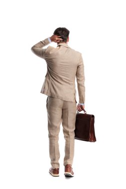 Kafası karışmış bej takım elbiseli, deri çantalı ve beyaz arka planda kaşınan kafası olan bir adam.