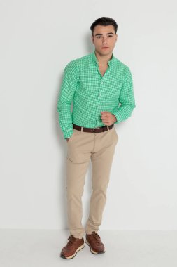 Sıradan bir adam beyaz arka plana bakarken el ele poz veriyor.