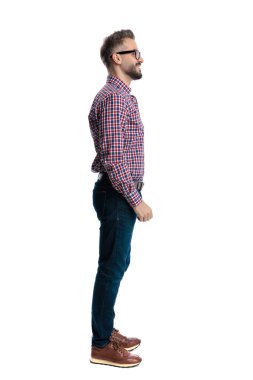 Gözlüklü ve ekose gömlekli mutlu bir adamın beyaz arka planda dikilip gülümsemesi.