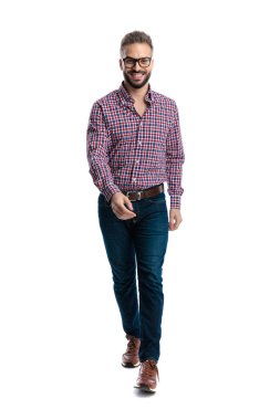 Gözlüklü ve ekose gömlekli mutlu bir adam beyaz arka planda izole edilmiş kameraya gülümserken ileri doğru yürüyor.