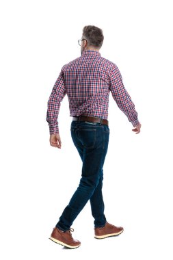 Modern adamın beyaz arka planda izole edilmiş ekose gömlek ve kot pantolon giyerek yürüyüp gidişinin arka görüntüsü.