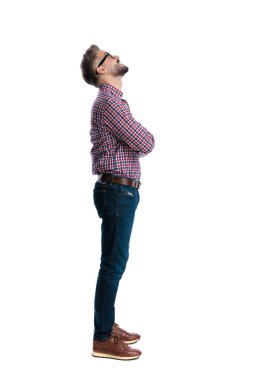 Ekose gömlek ve gözlüklü, kolları çapraz duran, beyaz arka plana bakan düşünceli sıradan bir adamın yan görüntüsü.