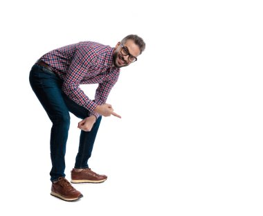 Gözlüklü neşeli bir adam öne doğru eğiliyor ve beyaz arka planda ileriye bakıyor.