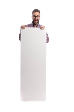 Gözlüklü ve ekose gömlekli neşeli bir adam elinde kocaman boş bir ilan panosuyla beyaz arka planda ileriye bakıyor.