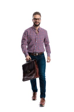 Kendine güveni tam, gözlüklü, deri çantalı ve beyaz arka planda yürüyen bir adam.