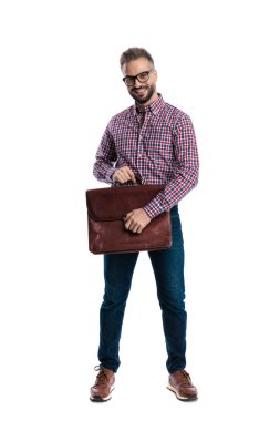 Deri evrak çantası tutan ve gülümseyen, beyaz arka planda tek başına ileriye bakan sıradan bir adam.