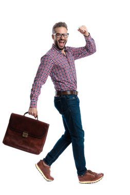 Çantayla yürüyen ve zaferi kutlayan heyecanlı sıradan bir adamın beyaz arka planda ileriye bakışıyla yan görünüşü