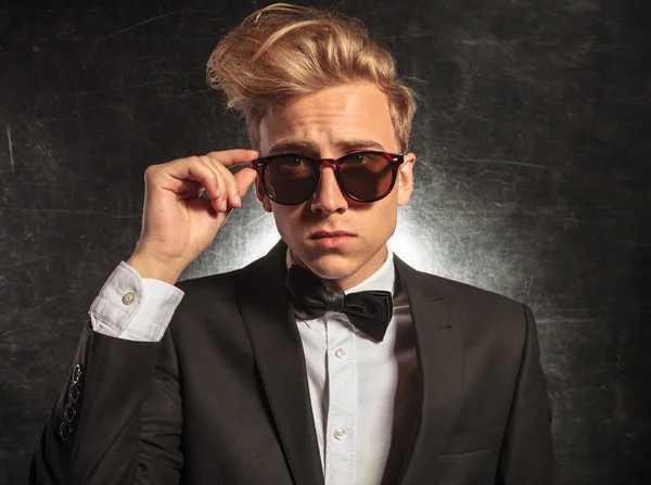 Joven en el estudio con esmoquin mientras arregla gafas de sol —  Fotos de Stock