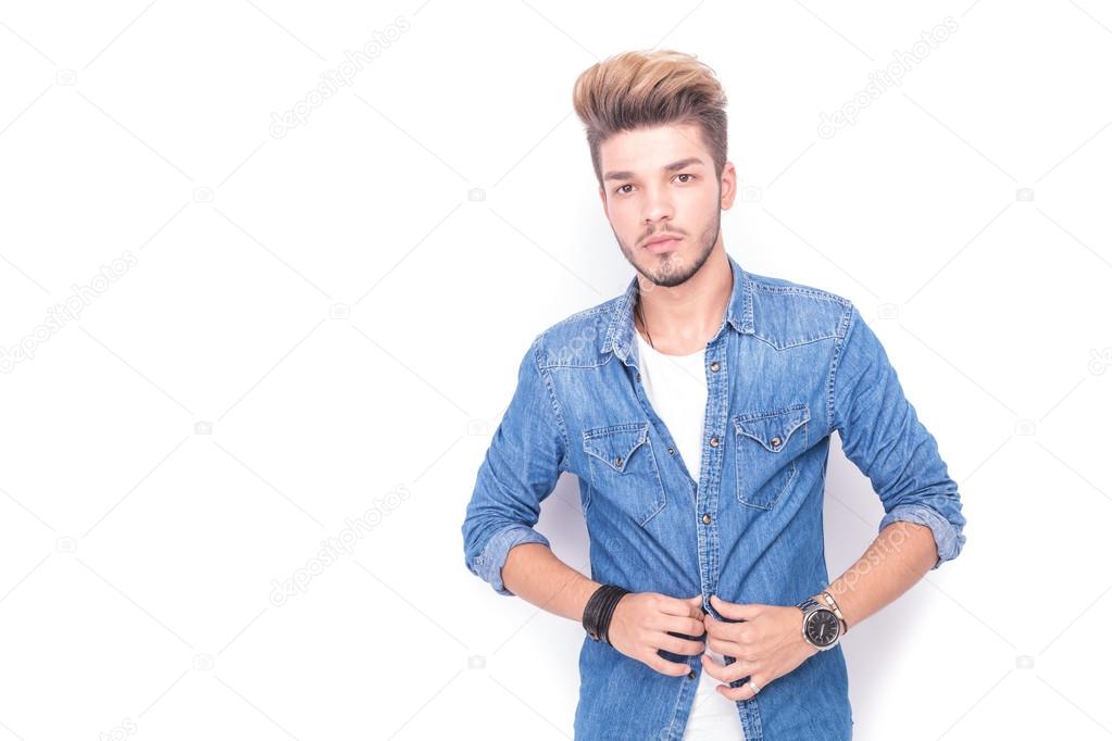 young casual man unbuttoning his jeans shirt