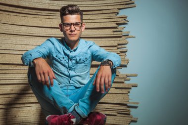Studio elleriyle dizlerinin üzerinde oturan akıllı adam