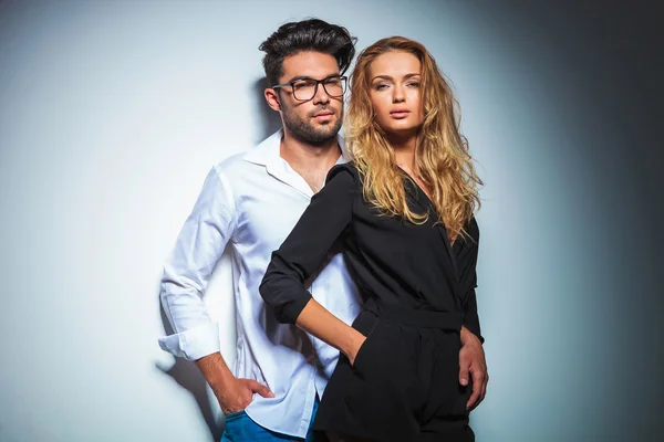 Couple pose in studio with hands in pockets while looking at the — Stock Photo, Image