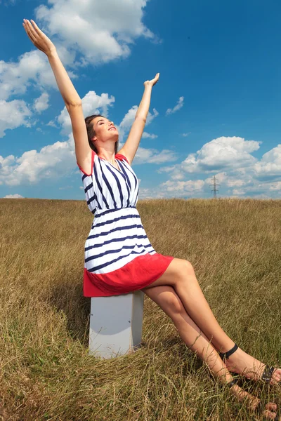 Young woman sitting while holding her hands up — Stock Photo, Image