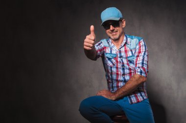 positive old casual man in trucker hat making  ok sign