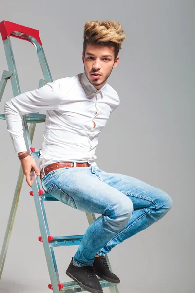 Young boy in jeans and white shirt climb on a ladder — Stock Photo, Image