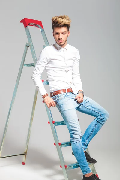 Man leaning against a ladder while posing in studio — Stock Photo, Image