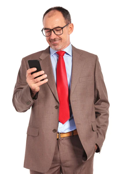 Smiling old businessman reading a message or texting — Stockfoto