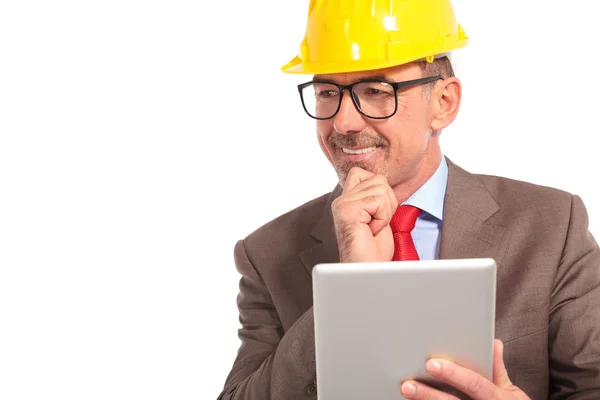 Construction engineer with tablet pad looks to side and smiles — 图库照片