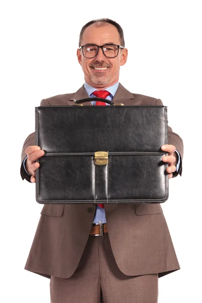 Happy old businessman showing his briefcase — Zdjęcie stockowe