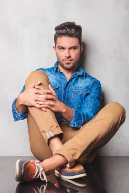 stylish man sitting in studio background legs crossed holding hi