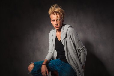 sad young man wearing rugged jeans posing in studio background