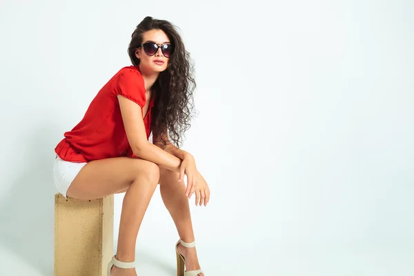 Woman wearing sunglasses and heels while sitting with hands cros — Stock Photo, Image