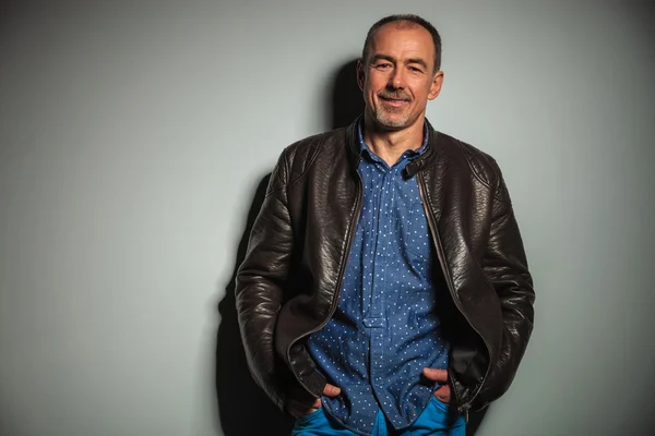 Sorrindo velho homem casual em jaqueta de couro com as mãos nos bolsos — Fotografia de Stock