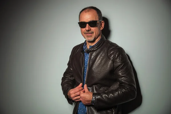 Sorrindo homem casual sênior fechando sua jaqueta de couro — Fotografia de Stock