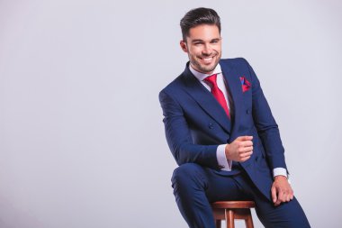 eğilerek oturan ve gülümseyen iş adamı