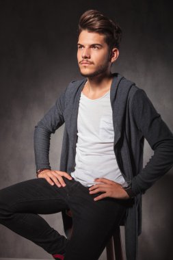 Studio ile oturan genç adam uzakta bel seyir eller