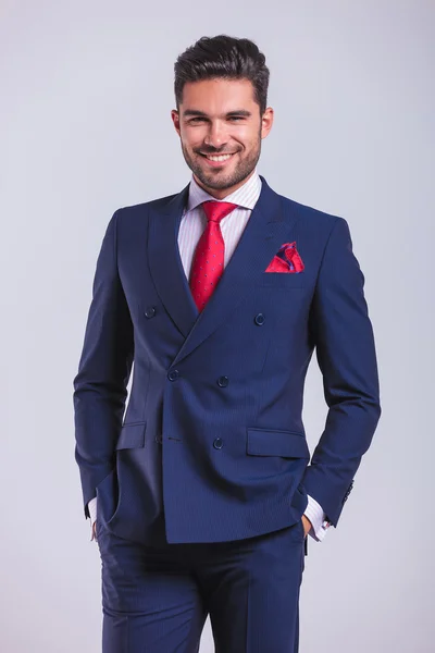 Homem de negócios sorrindo e posando com as mãos nos bolsos — Fotografia de Stock