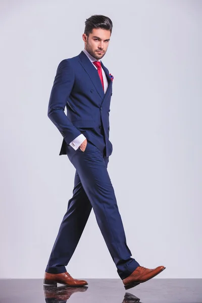 Serious man in suit walking with hands in pockets — Stock Photo, Image