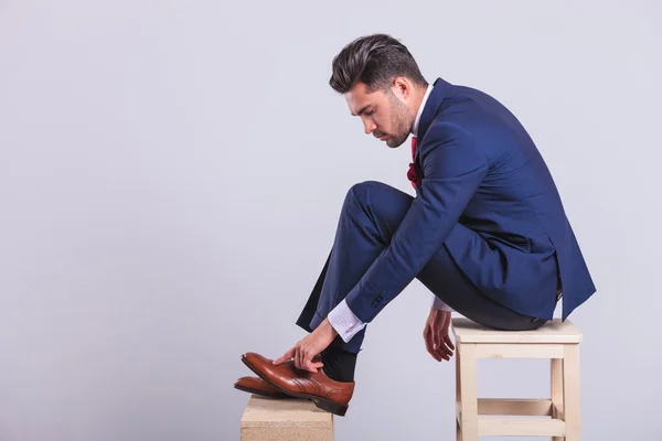 Hombre de traje sentado en la silla en el estudio limpiando sus zapatos — Foto de Stock