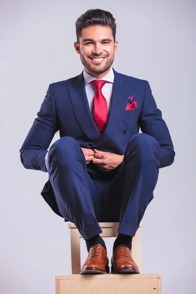 Man sitting on a chair while unbuttoning his jacket — Stock Photo, Image